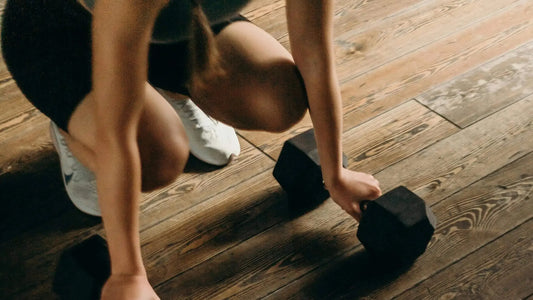 female crouching with dumbbells