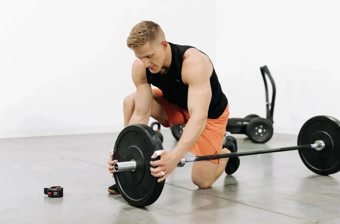 Man fixing bumper plates to barbell