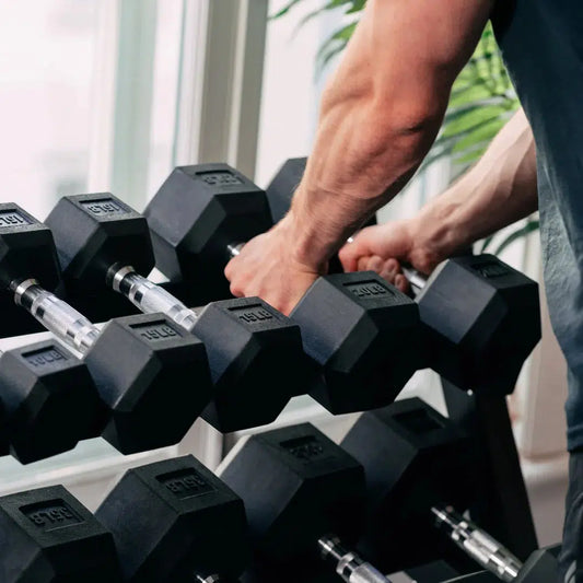 Man selecting hex dumbbells from dumbbell rack