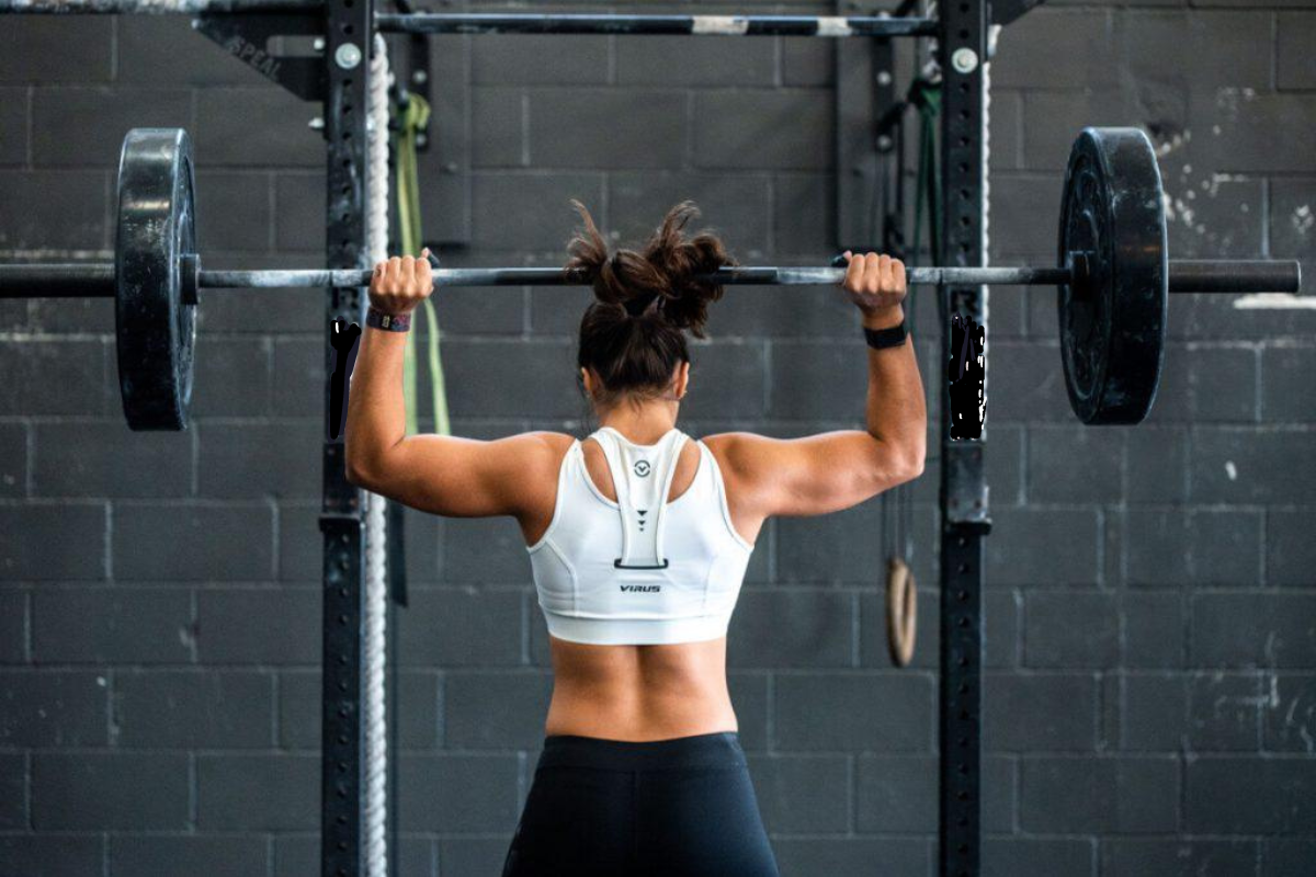female lifting a barbell and bumper plates at a power rack