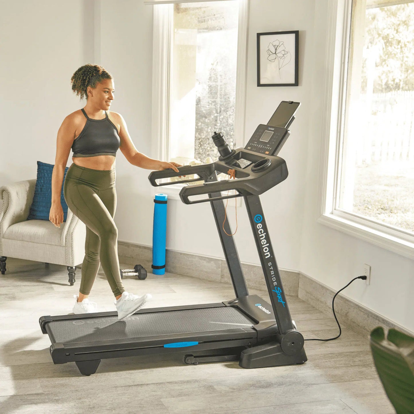 Woman stepping on stride 20 treadmill in home with large windows and soft lighting