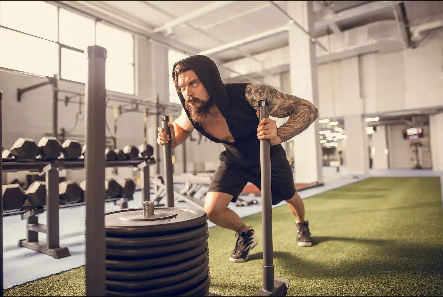 Man pushing a weighted sled on an artificial turf track